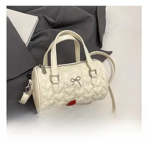 Détail d'un sac à main blanc avec surpiqûres en cœur et nœud argenté sur fond de costume