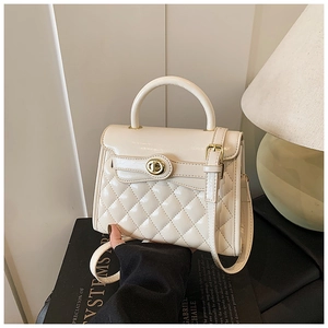 Détail du sac matelassé crème avec finition vernie brillante et fermoir doré rotatif
