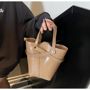 Detail of vintage camel bucket bag featuring glossy leather and metallic rivet accents