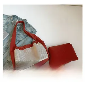 Détail du sac à bandoulière rouge avec mesh blanc et pochette assortie sur denim