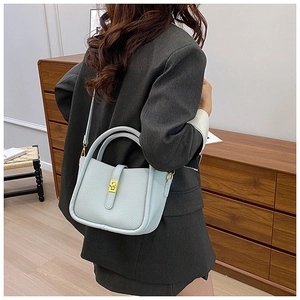 Detail of light blue lychee pattern leather bag with gold buckle and wood background