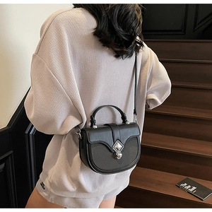 Gros plan d'un sac besace noir en cuir PU avec fermoir métallique vintage sur escalier