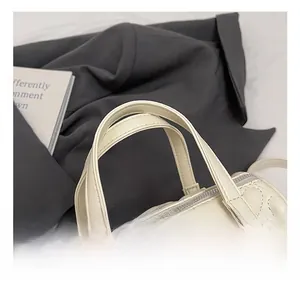 Détail d'un sac à main blanc avec coutures en forme de cœur et pendentif nœud en métal