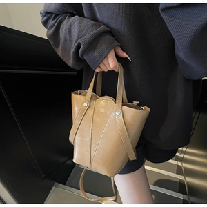 Detail of khaki bucket bag with silver studs and cross-strap design for women