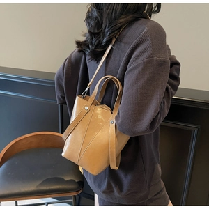 Detail view of a vintage tan leather bucket bag being worn by a model in a minimal setting