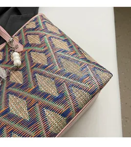 Detail of colorful woven tote bag featuring geometric patterns and pearl beaded charm