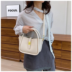 Close-up of cream white lychee leather mini tote with a gold twist lock on crossbody bag