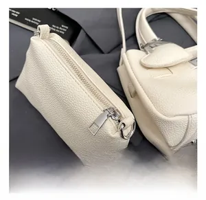 Détail de la fermeture éclair argentée et de la texture cuir sur le sac à main beige