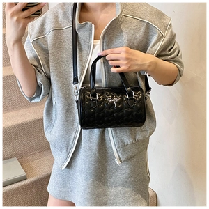 Détail du sac Boston cylindrique noir avec matelassage en cœur et nœud argenté chic