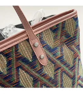 Close-up of geometric woven pattern with pink leather handle and rivet details on bag