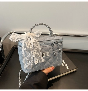 Detailed macro of quilted denim box bag with lace bow and silver metallic handle