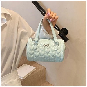 Détail du sac à main vert menthe avec matelassage en cœur et nœud métallique élégant