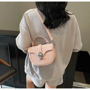 Vue détaillée du sac besace rose avec fermoir argenté porté à l'épaule par un mannequin