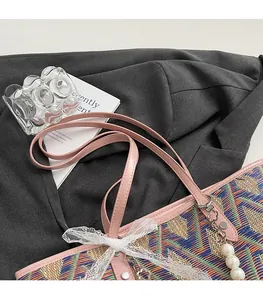 Detail of woven tote bag with pink leather strap, lace bow and large pearl pendant charm