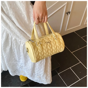 Détail du sac boston jaune vif avec matelassage cœur et décoration nœud doré