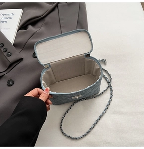 Detail view of denim box bag interior with herringbone lining and chain strap