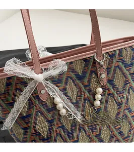 Close-up of woven tote bag featuring geometric patterns with pearl and lace bow charms