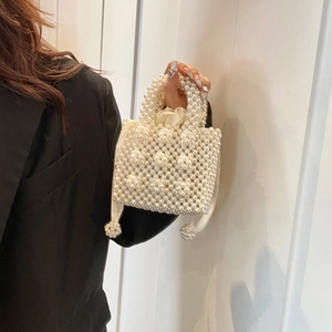 Sac à main élégant en perles ivoire avec doublure à cordon tenu par un modèle en noir