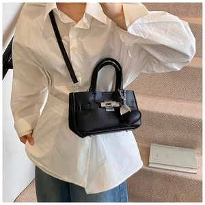 Détail du sac à main noir en cuir grainé avec fermoir argenté et breloque en cœur