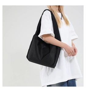 Vue détaillée du sac bandoulière en maille noire porté pour montrer la taille et le drapé