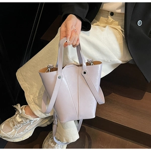 Detail of lavender leather bucket bag with adjustable strap on a model near stairs