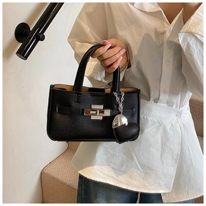 Détail d'un sac à main en cuir grainé noir avec fermoir argenté et breloque cœur