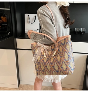 Detail of woven tote bag with blue geometric pattern and pink leather handle with pearls