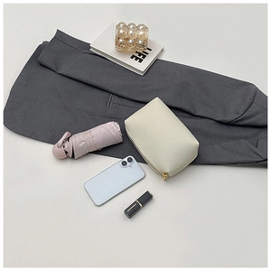 Chic beige lychee leather makeup pouch with gold zipper shown with fashion accessories