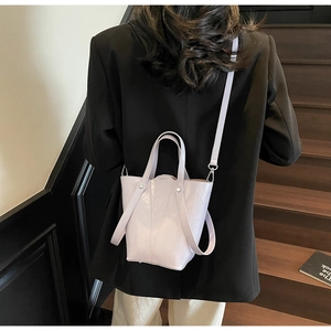 Model wearing a light purple glossy leather bucket bag with a chic minimalist design
