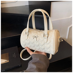Détail du sac boston matelassé cœur crème avec nœud argenté et finitions métalliques