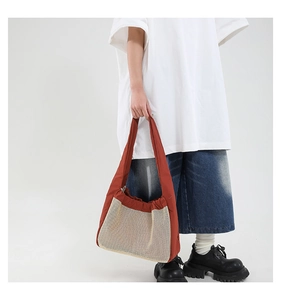 Détail du sac cabas en mesh et tissu contrasté porté par un mannequin en studio