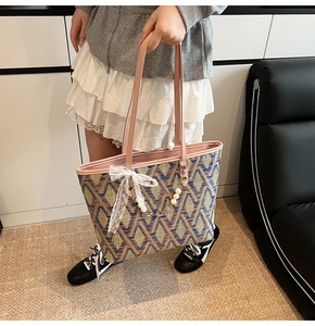 Detail of colorful geometric woven pattern tote bag with pink handles and lace charm
