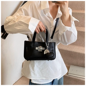 Détail du sac à main en cuir grainé noir avec fermoir rotatif argenté et pendentif