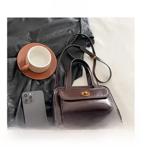 Detail view of a vintage dark brown leather crossbody bag with a metal twist lock closure