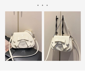 Detail of cream patent leather crossbody bag with bow decoration and pearl chain strap