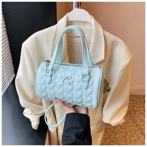 Détail du sac à main matelassé cœur bleu clair avec nœud métallique et surpiqûres