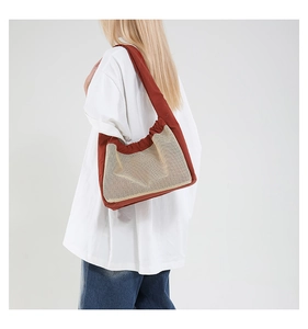 Détail d'un sac à bandoulière en maille beige avec lanières rouges porté par un mannequin chic