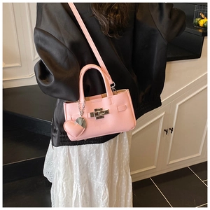 Vue détaillée du sac à main rose clair en cuir grainé avec fermoir argenté et charm coeur
