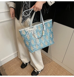 Detailed macro of woven tote bag with blue diamond pattern, lace bow, and pearl charm