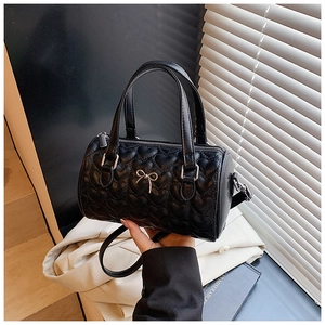 Détail du sac matelassé noir avec motifs de cœurs et pendentif nœud en métal argenté