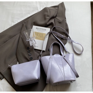 Detail of light purple glossy bucket bag set with mini pouch on a stylish setting