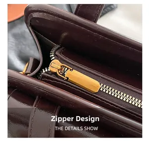 Detailed close-up of vintage gold metal zipper on premium dark burgundy leather handbag
