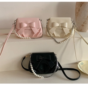 Detailed view of fashionable bow square bags with pearl chain in pink, cream and black