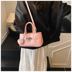 Vue détaillée du sac à main en cuir rose avec breloque cœur et fermoir argenté