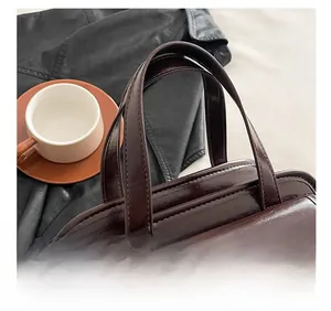 Detail of comfortable double handles and vintage metal twist lock on a retro leather handbag