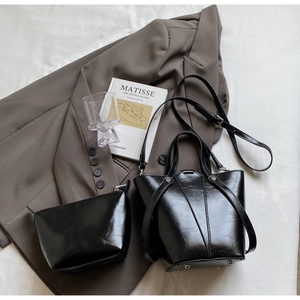 Detail of black matte leather bucket bag with metal feet and matching small pouch