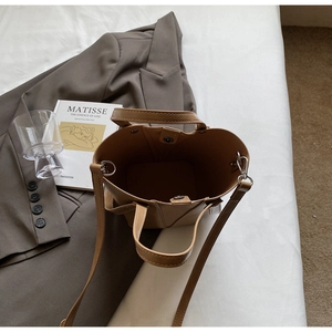 Detail of camel bucket bag showing adjustable strap and spacious interior in a lifestyle setting