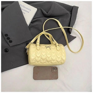 Détail du sac polochon jaune avec matelassage cœur et nœud argenté décoratif chic