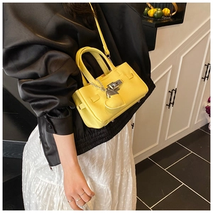 Détail du sac à main jaune en cuir avec fermoir argenté et breloque en forme de cœur