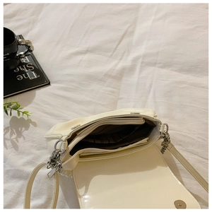 Internal view of cream crossbody bag showing three compartments and striped lining